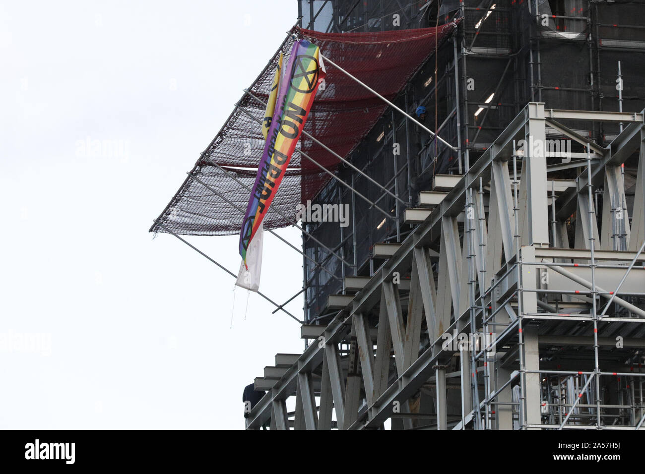Westminster, London, UK, 18 Oct 2019. A climate protester from Extinction Rebellion (XR) has climbed up Big Ben half way, fitted two banners and sits atop some scaffolding on the southeatern corner of the Elizabeth Tower, commonly known as Big Ben, of the Houses of Parliament. Police negotiators appear to be at the scene just above him. Credit: Imageplotter/Alamy Live News Stock Photo