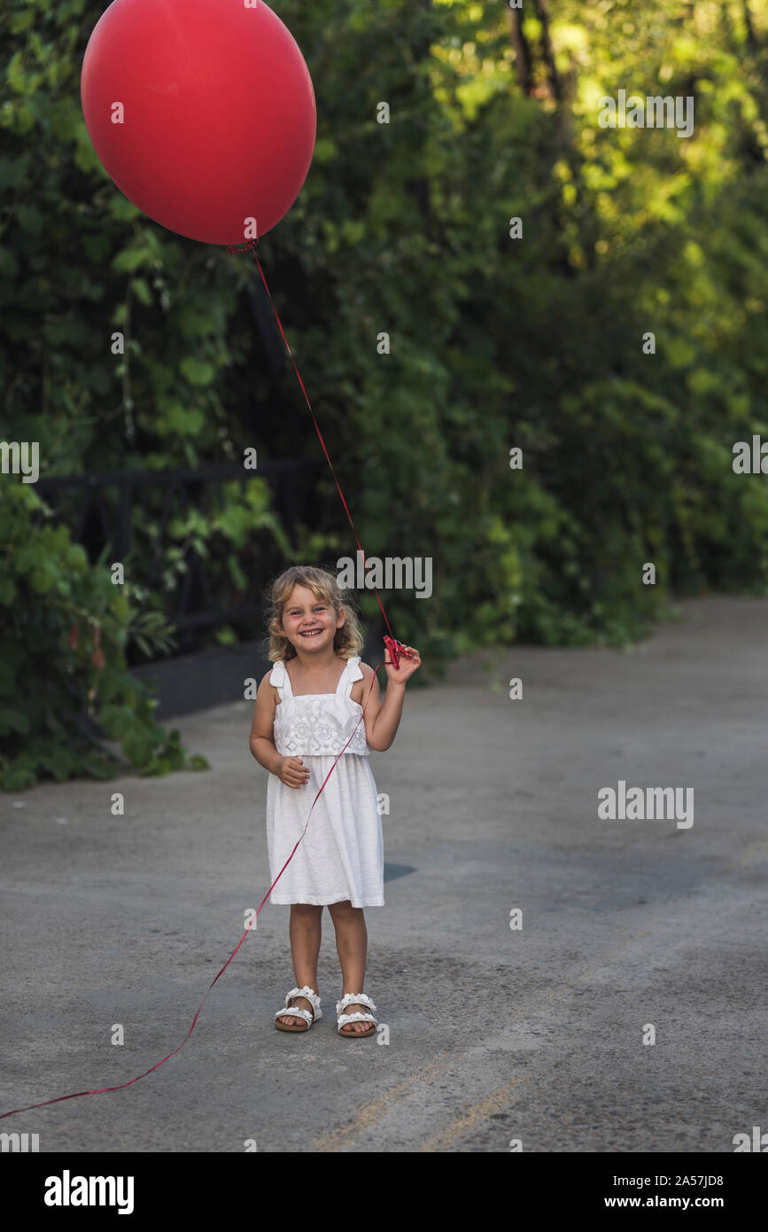 Young girl with big red balloon running on Steel Canyon Bridge Stock Photo
