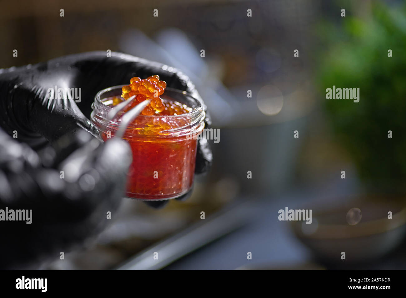 Food concept. The chef picks red caviar from a jar with tweezers. Selective focus. Shallow depth of field. The process of making spaghetti with seafoo Stock Photo
