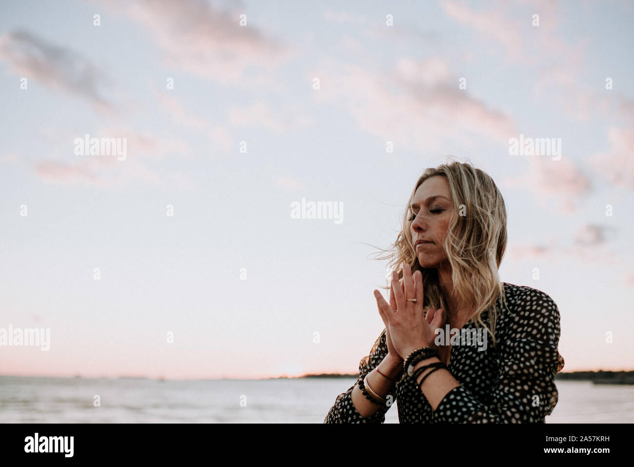 young woman on the beach in meditation at sunset Stock Photo