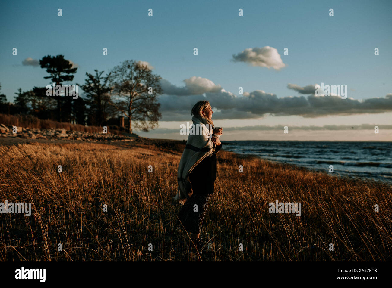 woman wrapped in a blanket on the beach Stock Photo Alamy