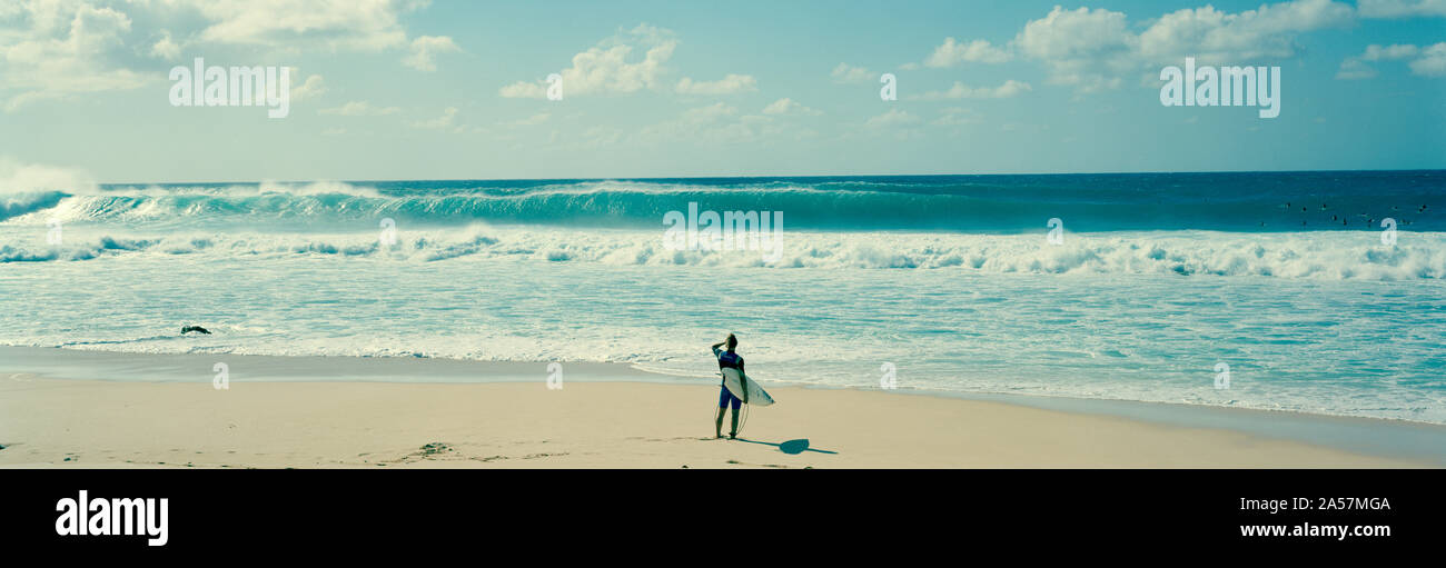 Surfer standing on the beach, North Shore, Oahu, Hawaii, USA Stock Photo