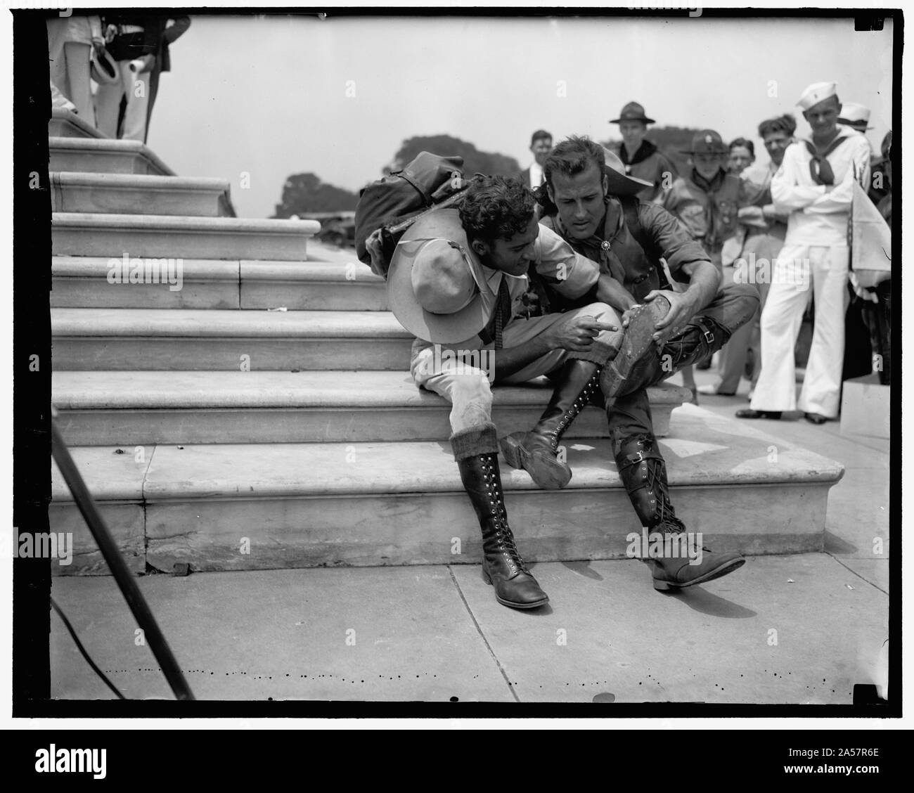 Walk 800 miles to attend Boy Scout Jamboree. Washington, D.C. June 16. Two Venezuelan Boy Scouts, Rafael Petit, left and Juan Carmona, right, examining their boots after tramping 25 miles a day for two years in order to attend the Boy Scout Jamboree in Washington the left Caraca, Januray 11, 1935 arriving in Washington today. Stock Photo