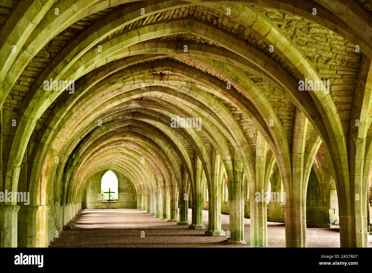 Fountains Abbey Cistercian monastery vaulted stone arches in ceiling of the monks cellarium with cross at window North Yorkshire England Stock Photo