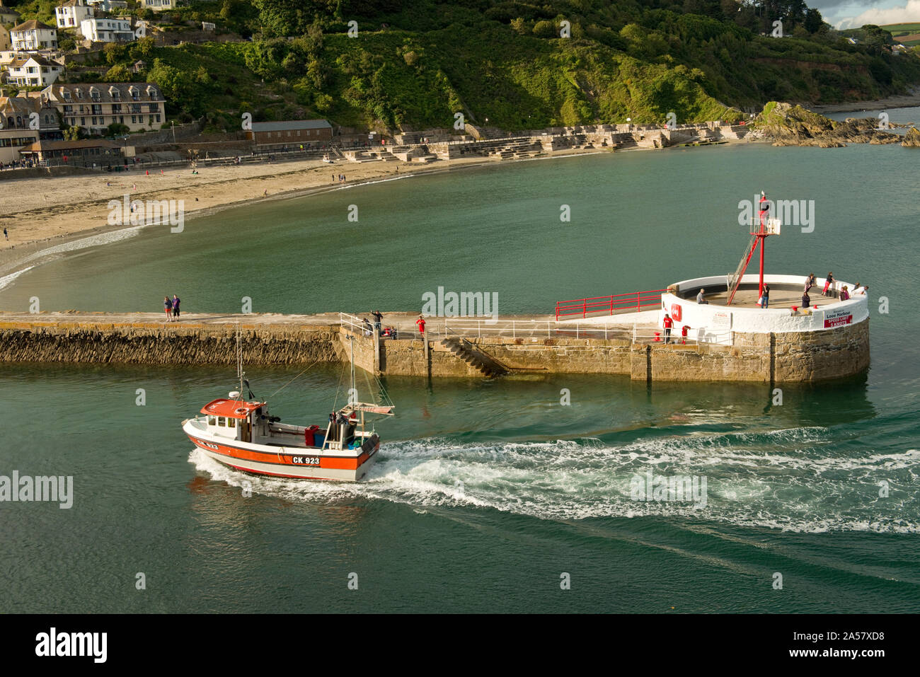 Fishing boat passing pier and entering Looe Harbour, South Cornwall, England, UK Stock Photo