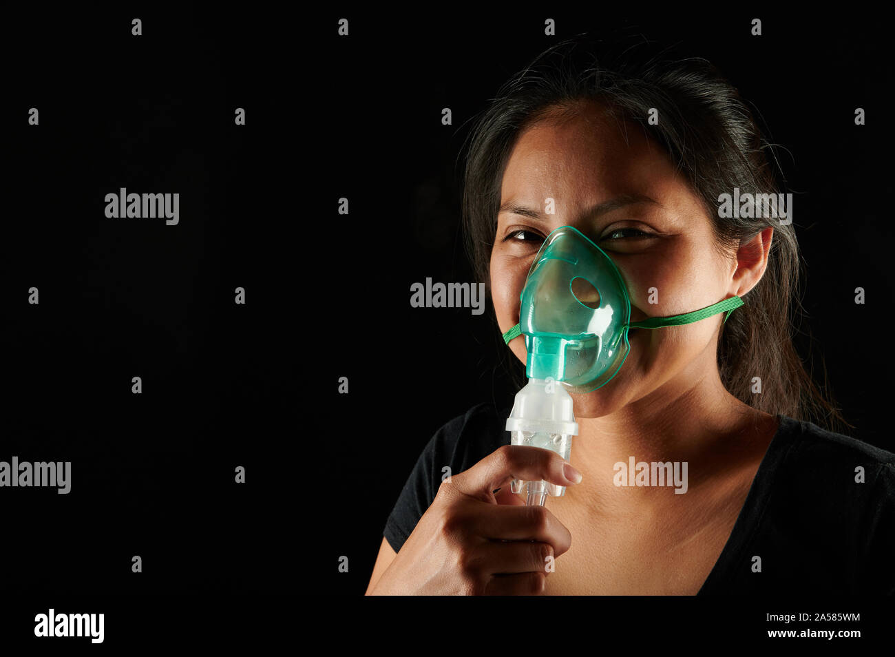 Portrait of young woman with medical mask isolated on black background ...