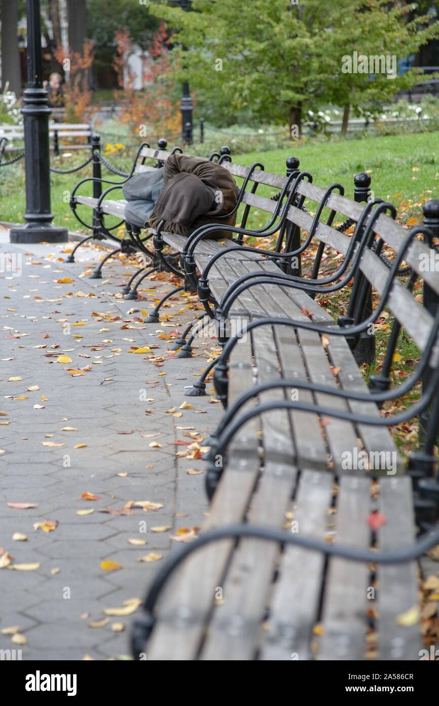 Vertical shot of a homeless person sleeping on a bench in Central park, New York City Stock Photo