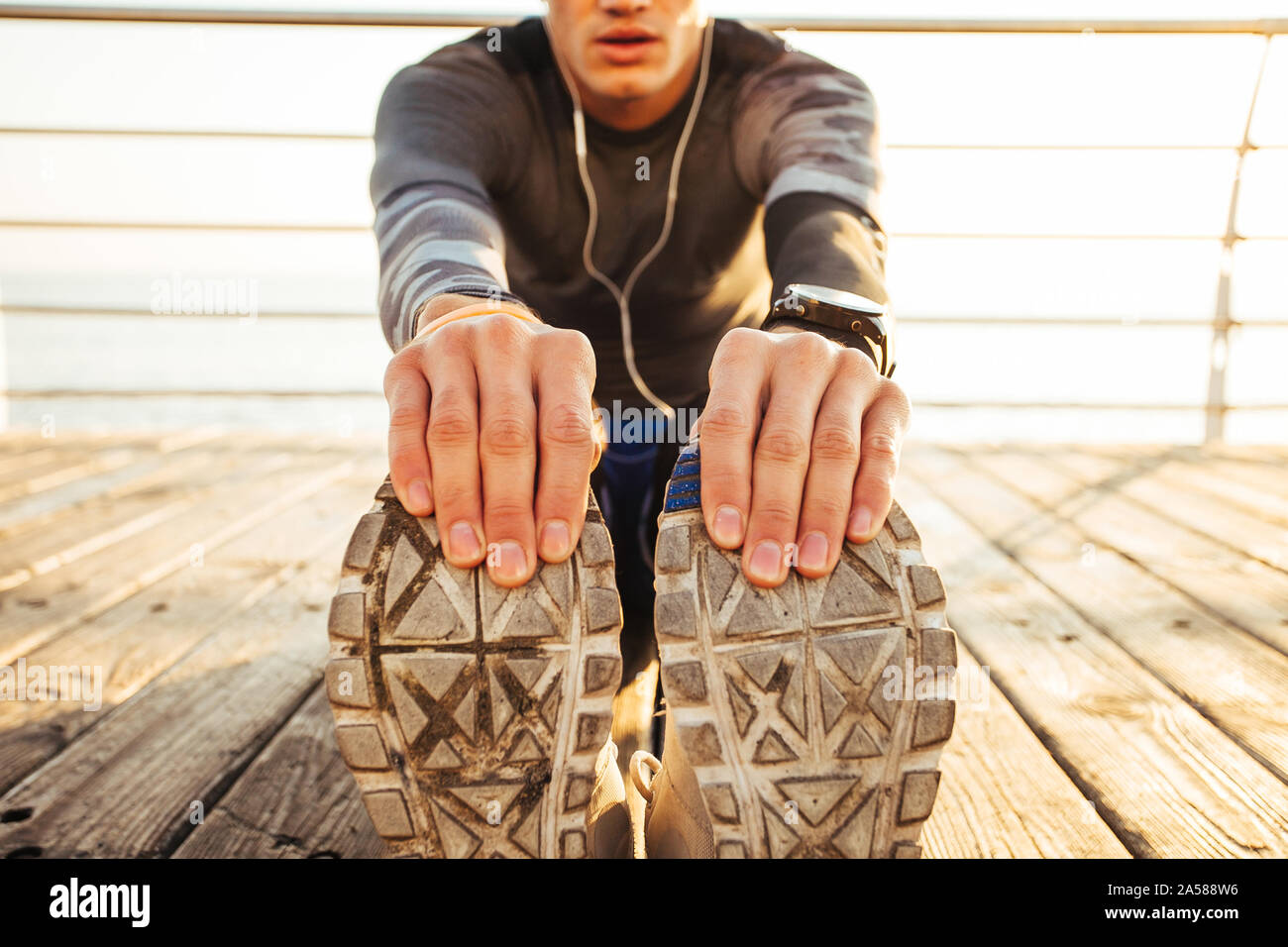 Fit handsome man  warming up in preparation for a workout run. Stock Photo