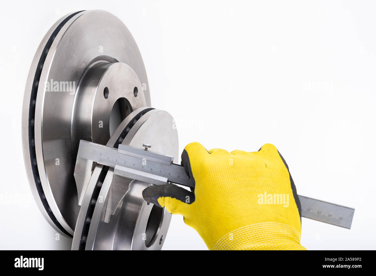 Measuring brake discs with a caliper. Car parts workshop measurements. Light background. Stock Photo