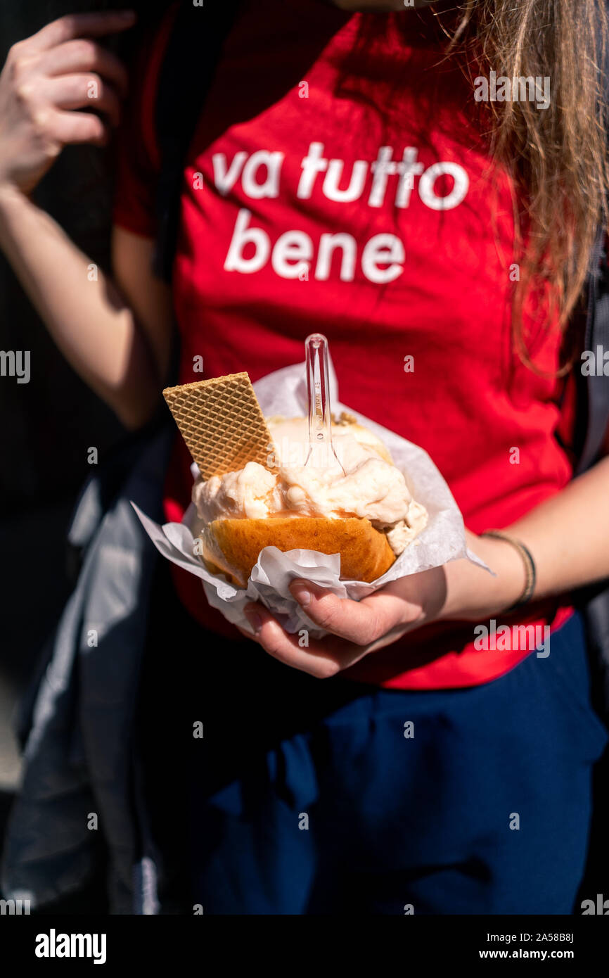 Young woman, tourist holding gelato or ice cream in brioche bun traditional Sicilian street food dessert in Palermo. Stock Photo