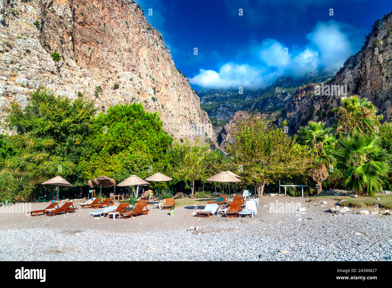 Sun loungers and straw parasols on the beach in the Butterfly Valley, Turkish Riviera, Turkey Stock Photo