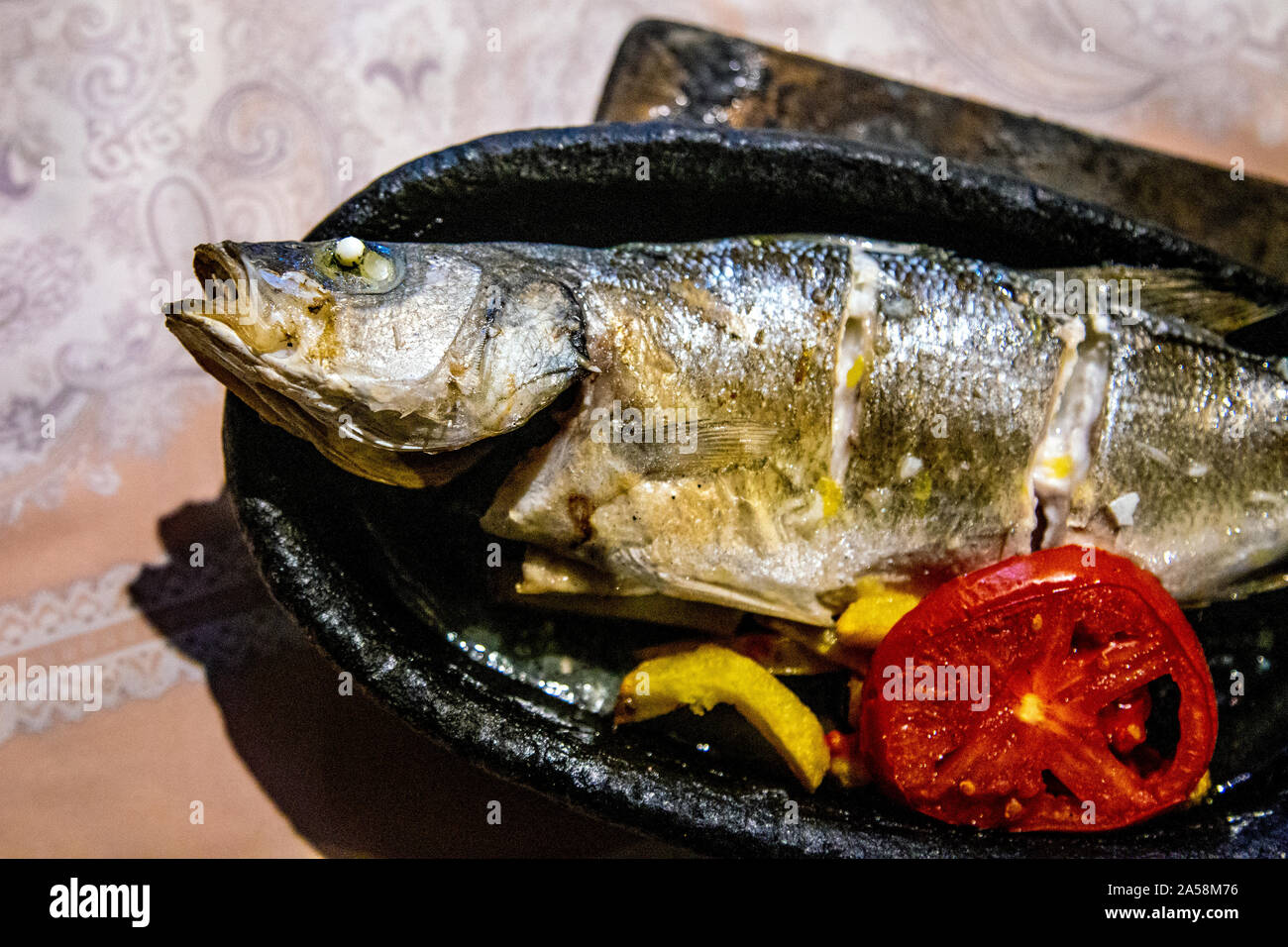Whole grilled sea bass dish at Karacaören Restaurant in the Karacaören Bay, Turkish Riviera, Turkey Stock Photo