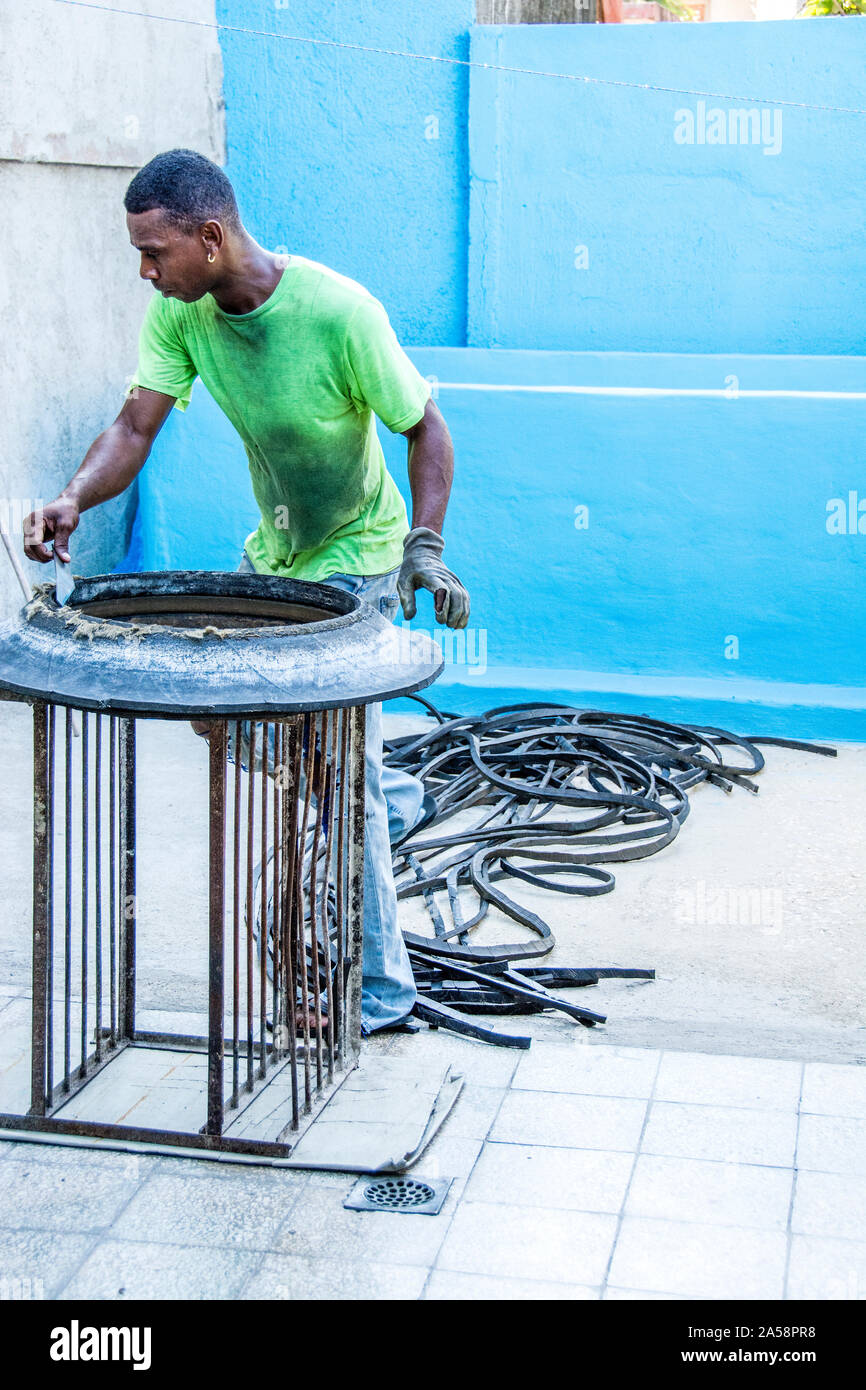 A man using a tool to cut rubber from tires that he then uses to sell