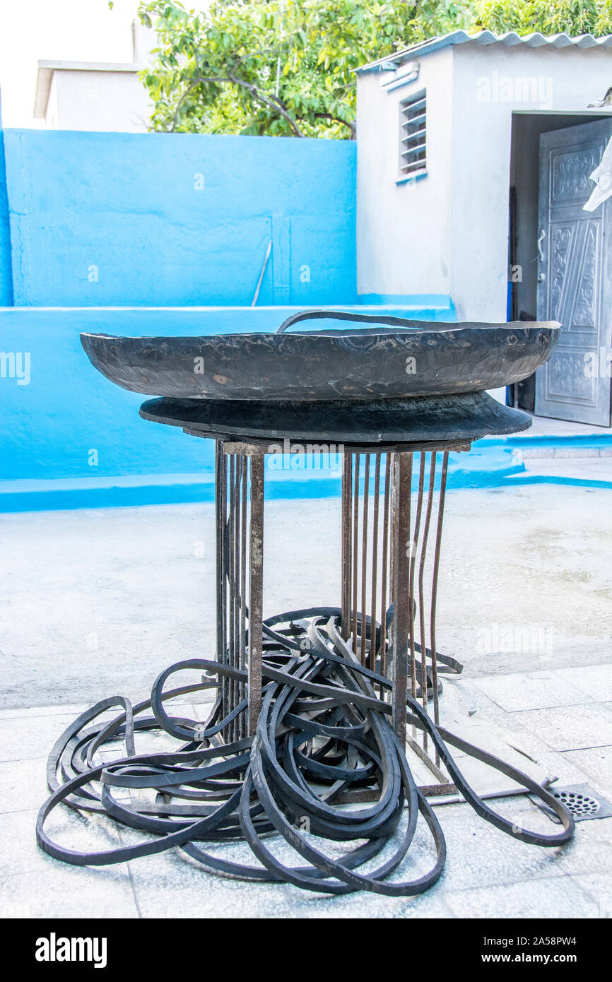 A man using a tool to cut rubber from tires that he then uses to sell