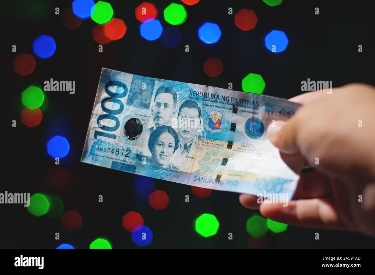 Close up shot of a hand holding or handing out a Filipino One Thousand Peso Cash during Christmas Holiday. Stock Photo