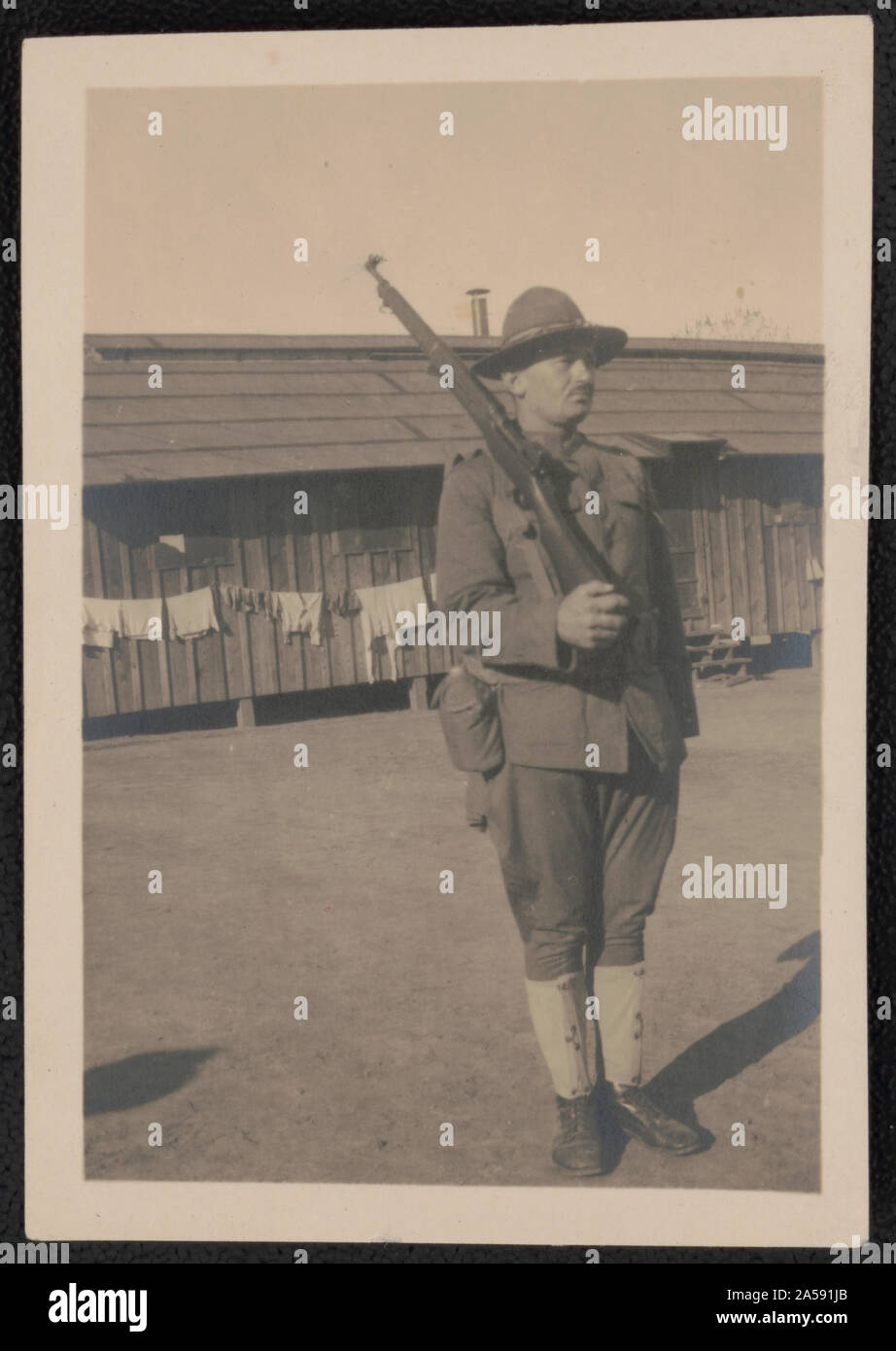 Unidentified soldier in uniform with rifle in front of barracks Stock Photo