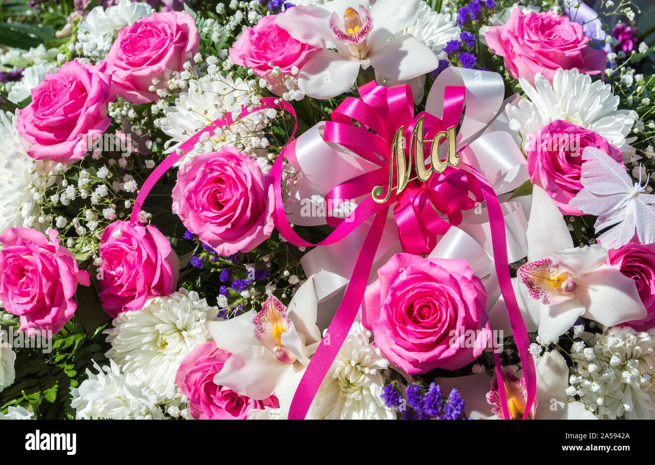 close up of pink, white and purple funeral flowers with the word MA in gold letters Stock Photo