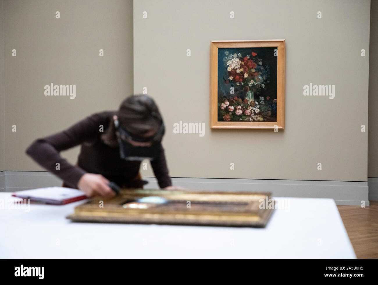 Potsdam, Germany. 18th Oct, 2019. Friederike Beseler, restorer, examines the construction of the exhibition 'Van Gogh. Stillleben' in the Barberini Museum is a painting by Vincent van Gogh, while behind it is the work 'Stillleben mit Wiesenblumen und Rosen, 1886/87'. The exhibition runs from 26 October 2019 to 2 February 2020. Credit: Christoph Soeder/dpa/Alamy Live News Stock Photo