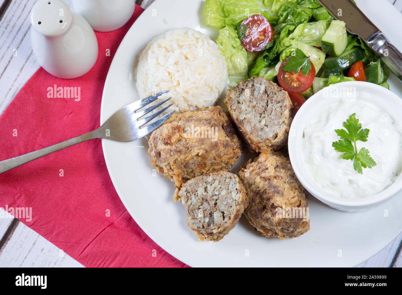 Traditional Turkish dish of Kadinbudu kofte, Cacik and Pilaf rice with Orzo served with fresh mixed salad Stock Photo
