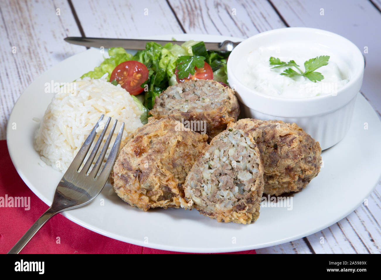 Traditional Turkish dish of Kadinbudu kofte, Cacik and Pilaf rice with Orzo served with fresh mixed salad Stock Photo