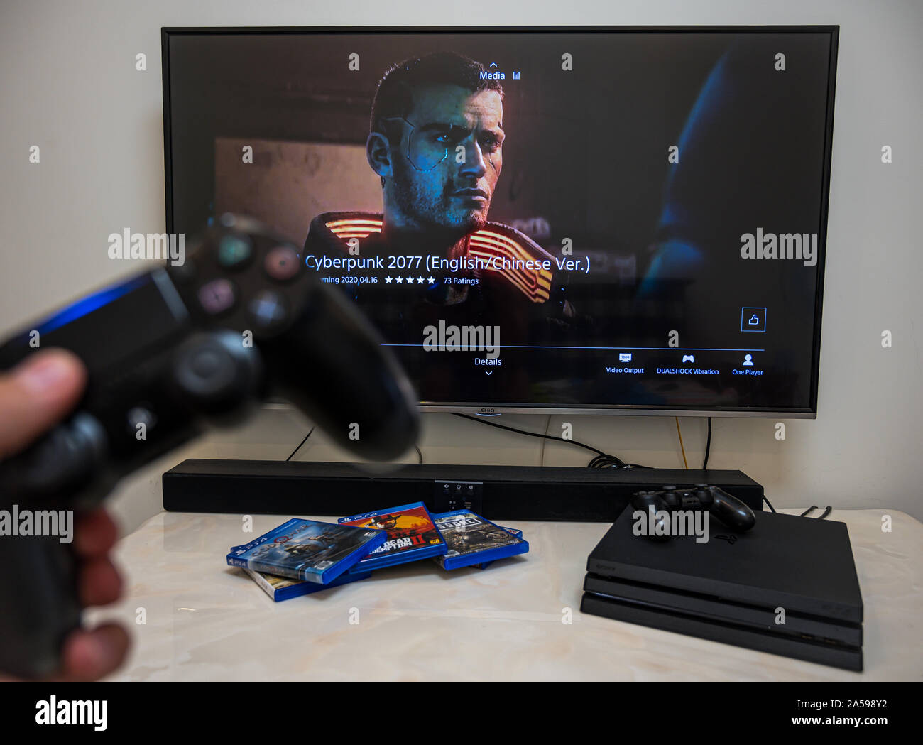 Pre-order, download, play Sony Play Station 4 Pro game Cyberpunk 2077 on the big LCD screen at home. Controller in the hand. Stock Photo