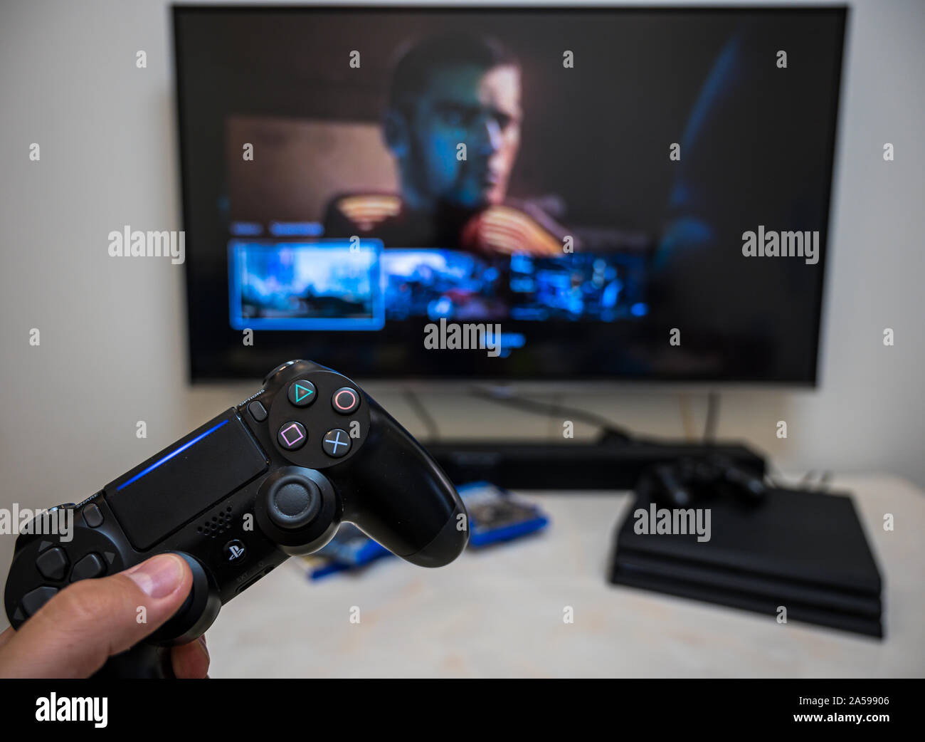 Pre-order, download, play Sony Play Station 4 Pro game Cyberpunk 2077 on the big LCD screen at home. Controller in the hand. Stock Photo