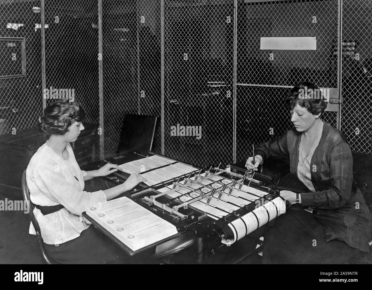Two women using check signing machine which signs checks issued by the ...