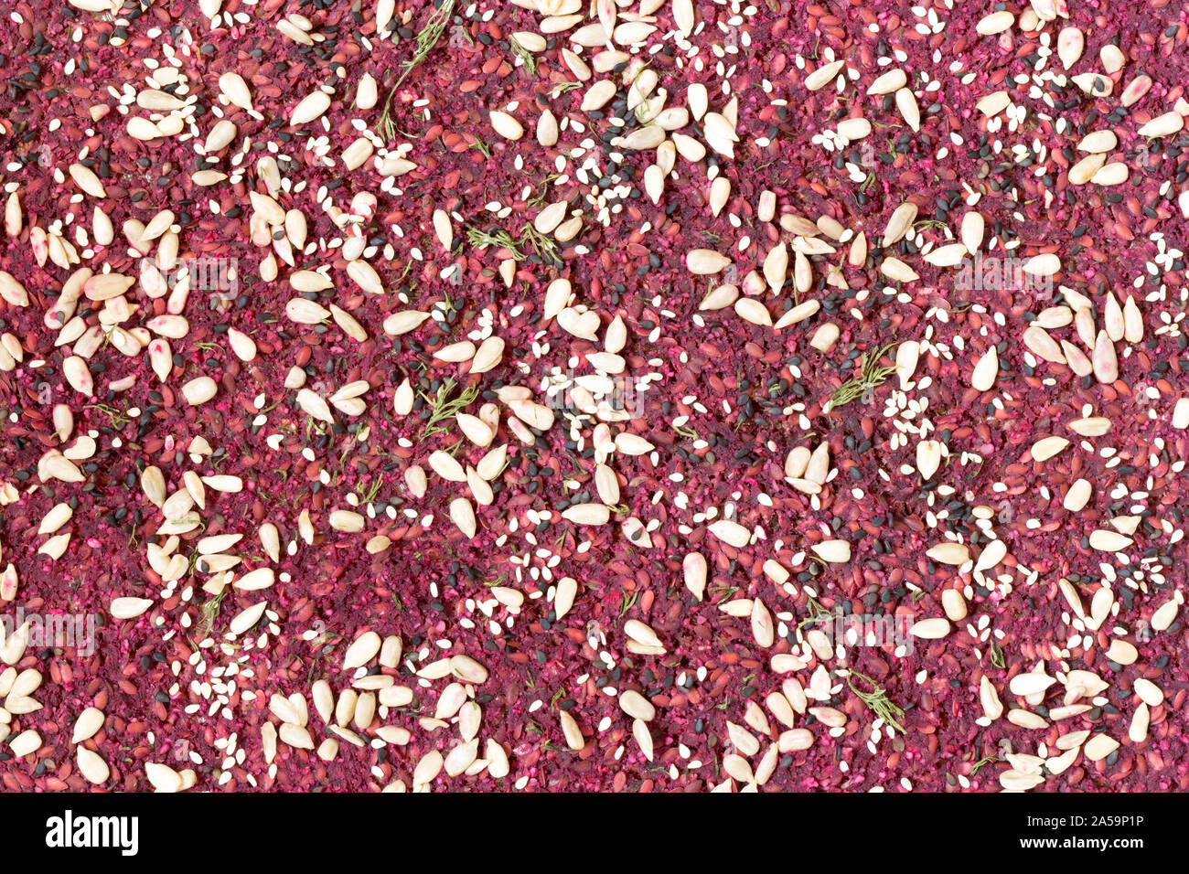 Raw foods bread background. Beet-onion bread with walnut made in dehydrator and sprinkled with seeds. Top view full frame texture. Veggie cracker Stock Photo