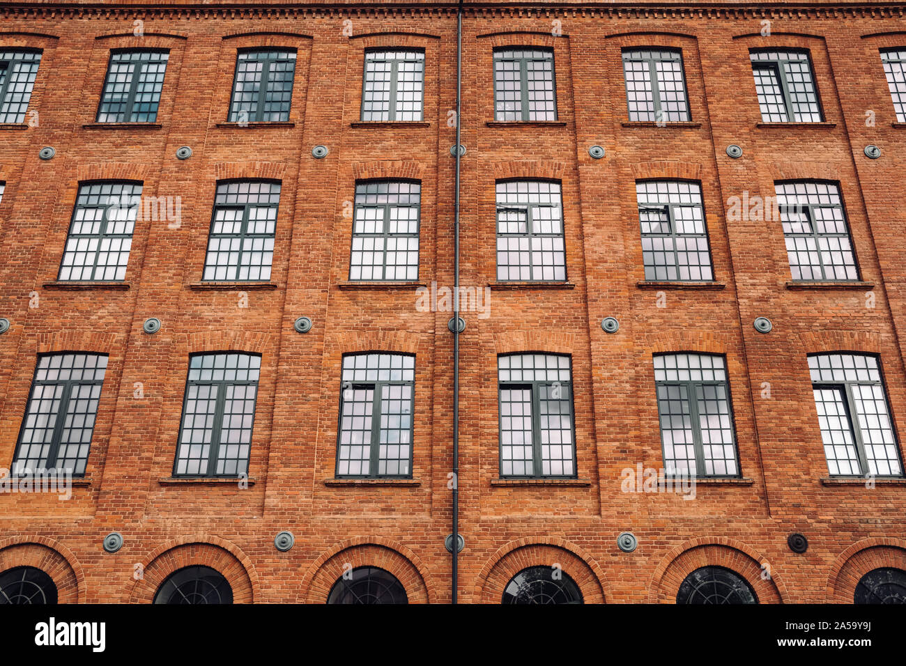 Red brick classic industrial building facade with multiple windows background.  Stock Photo