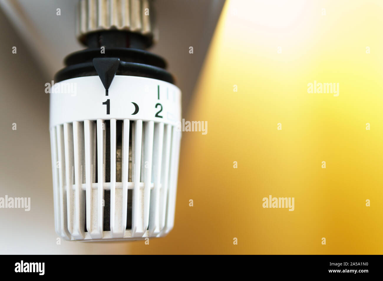 Heater thermostat valve set down to number one icon, symbol for saving money at heating costs or low temperature setting, closeup, horizontal format, Stock Photo