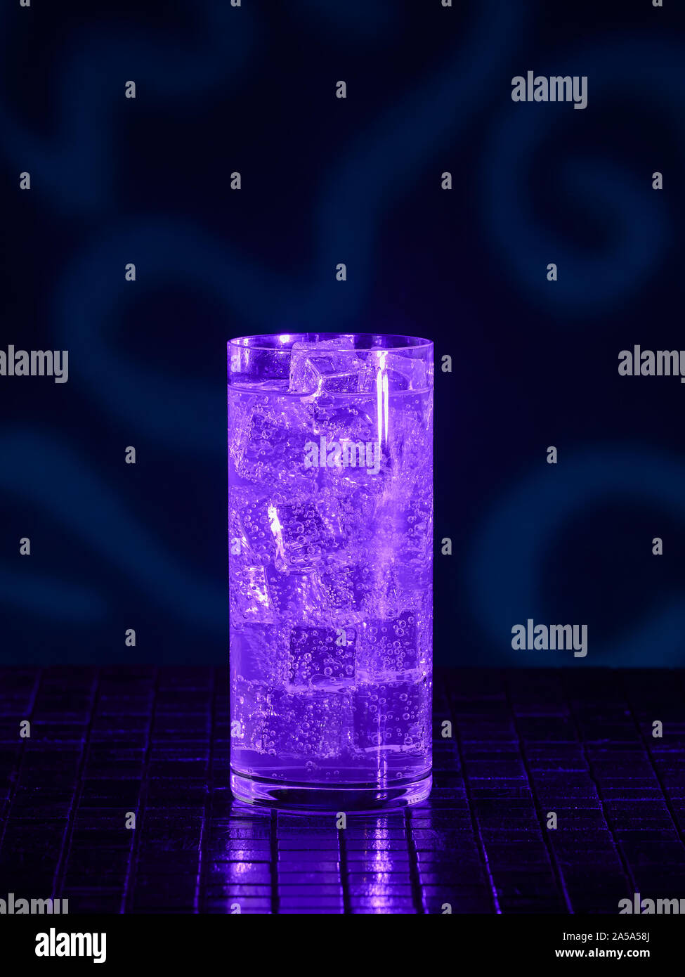 A glass of Mountain Dew under blacklight (UV) illumination. Glow in the dark drink. Stock Photo