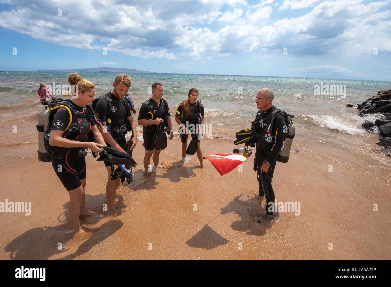 SCUBA diving instructor Anthony Manion entering the ocean with four students in front of the Grand Wailea Hotel on Maui, Hawaii. All five individuals Stock Photo