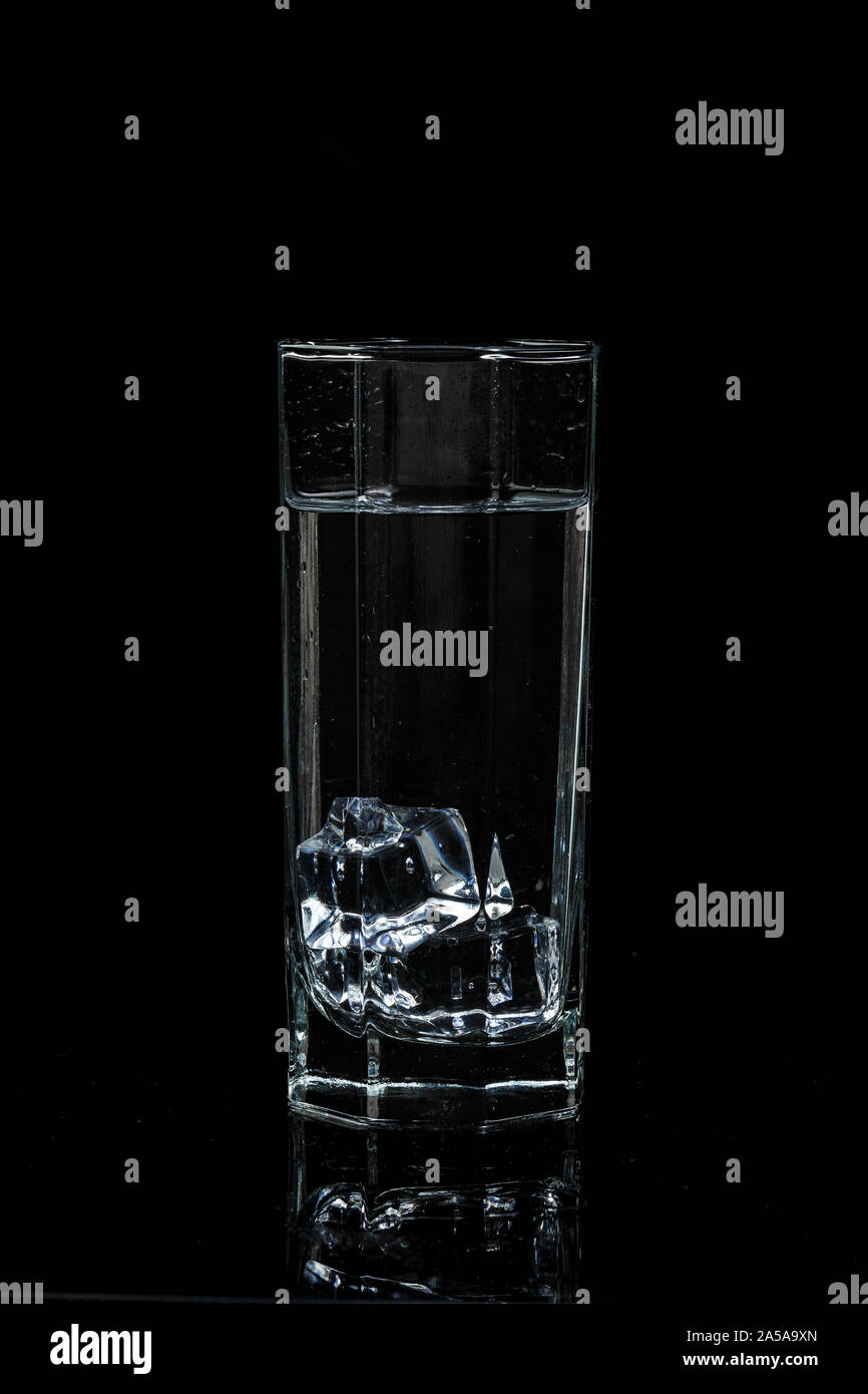 transparent water glass with ice cubes on black isolated glass ...
