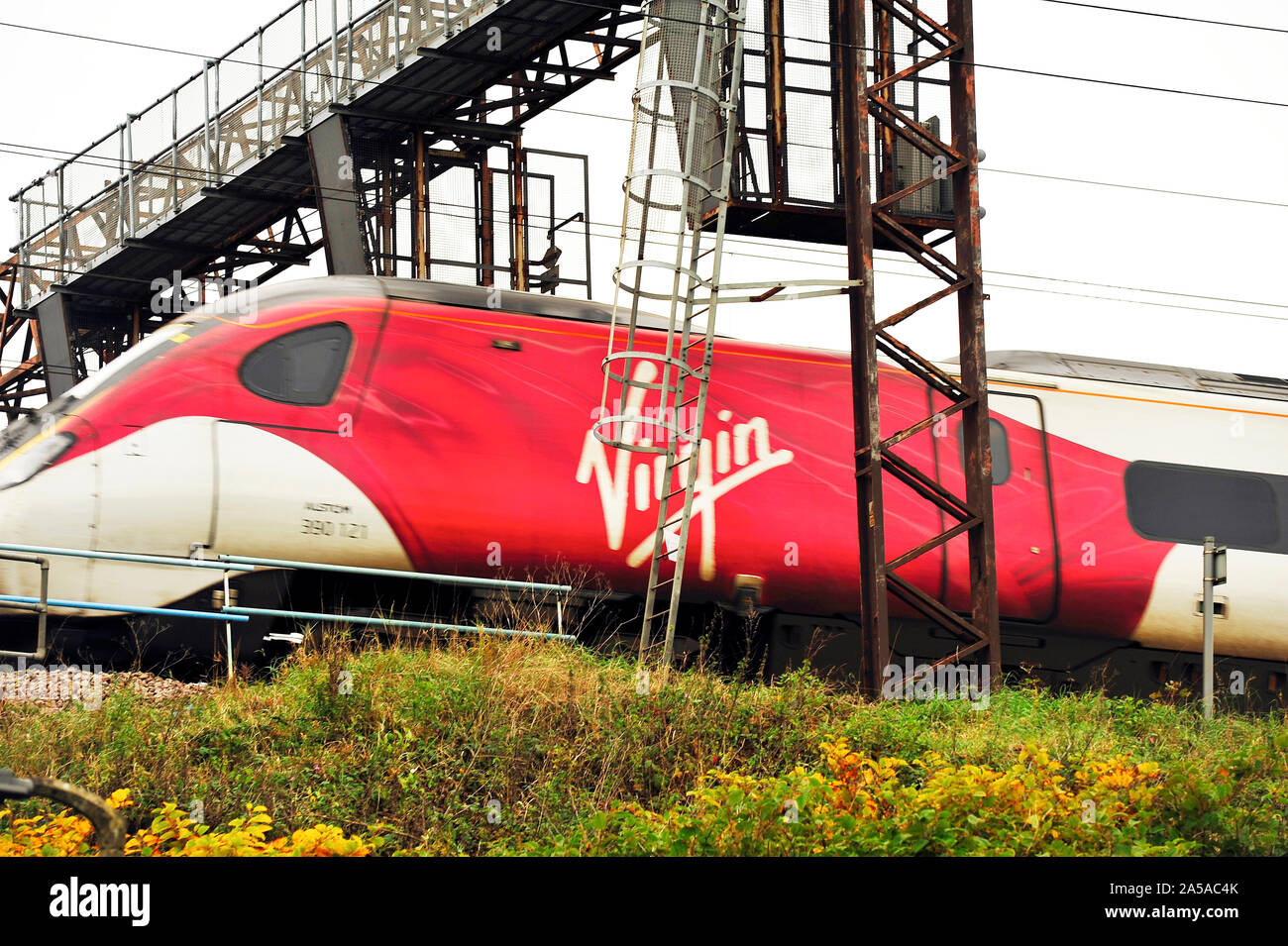 Virgin express train speeding beneath overhead gantry on main line through Preston Stock Photo
