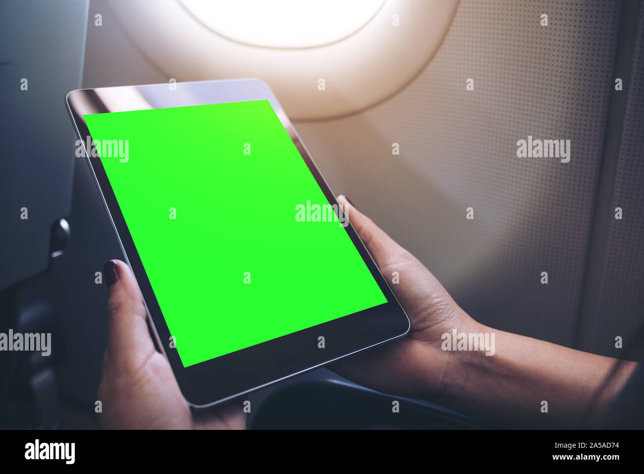 Download Mockup Image Of A Woman Holding And Looking At Black Tablet Pc With Blank Green Desktop Screen Next To An Airplane Window Stock Photo Alamy