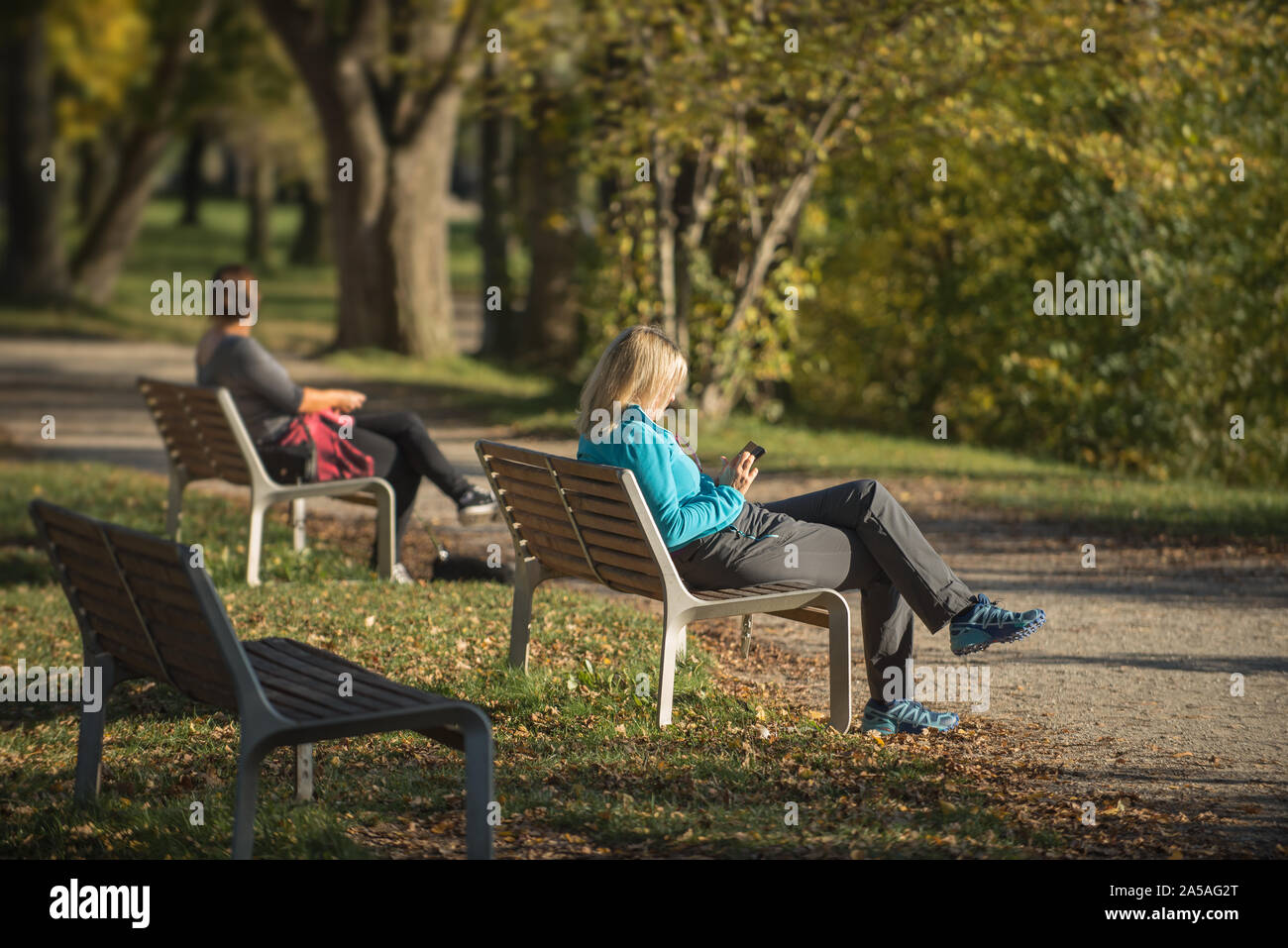 Two women sitting in the colorful park in the autumn season Stock Photo ...