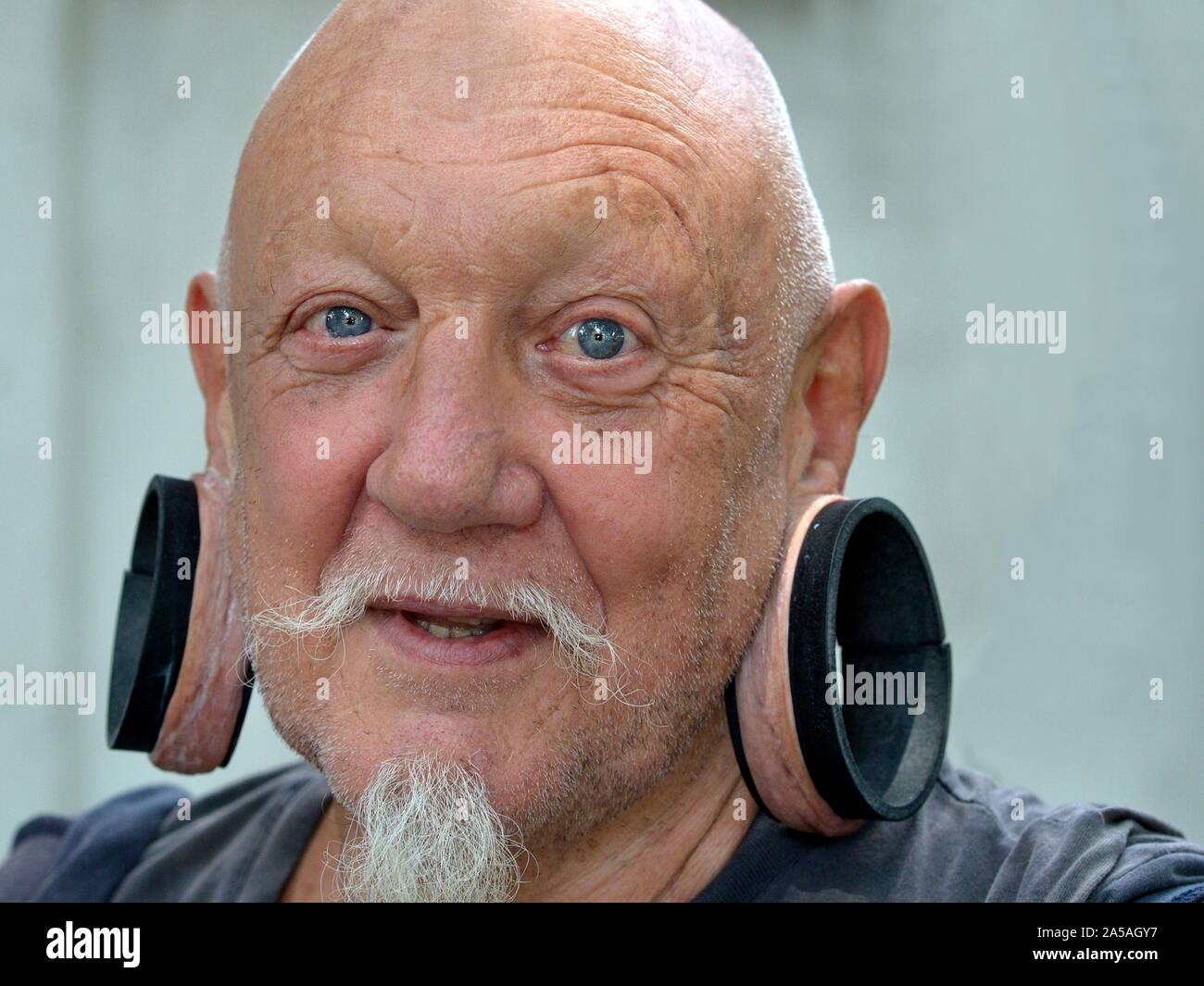 Elderly Caucasian man with huge elongated earlobes smiles for the camera. Stock Photo