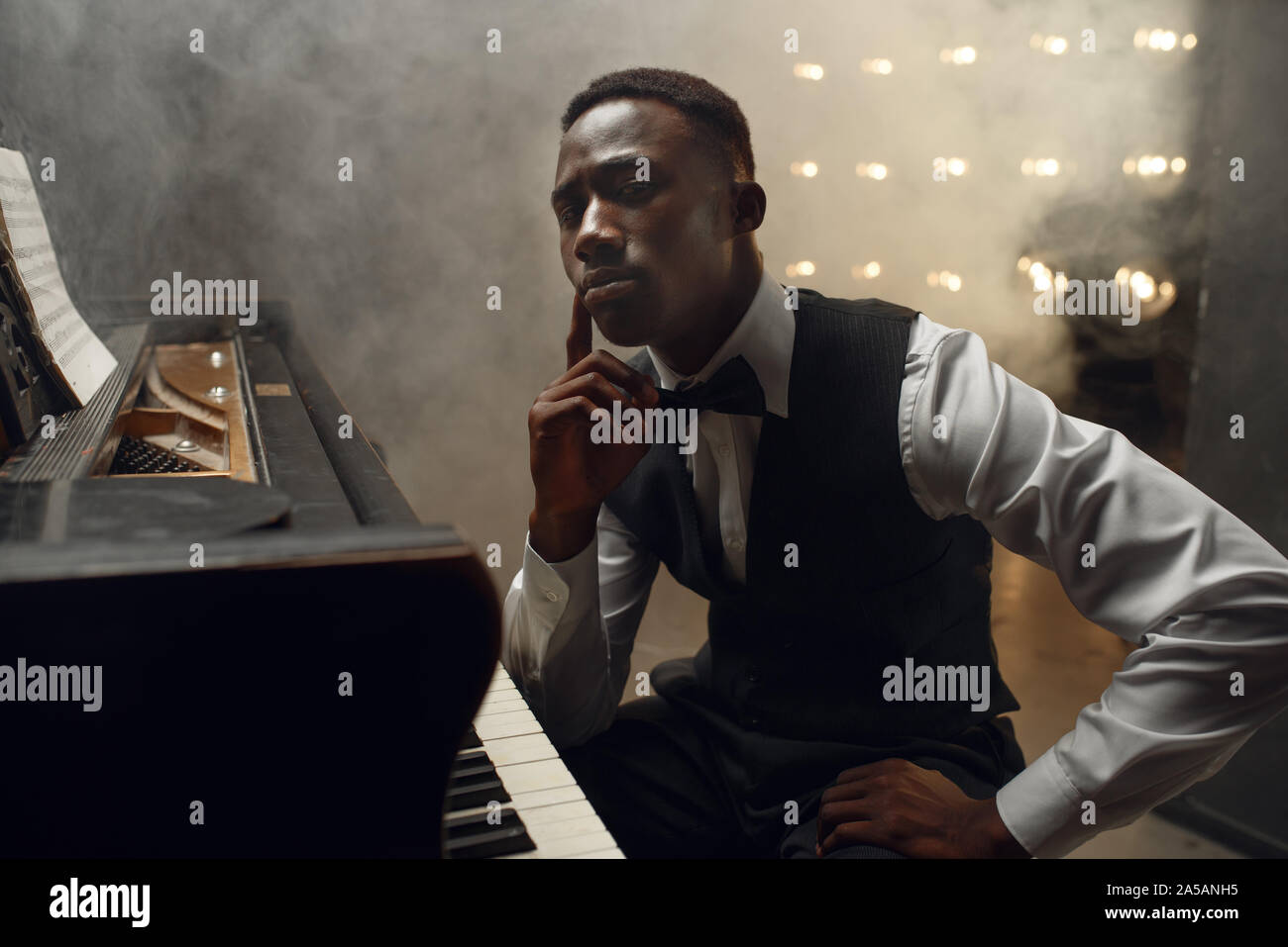 Black grand piano musician poses on the stage Stock Photo - Alamy