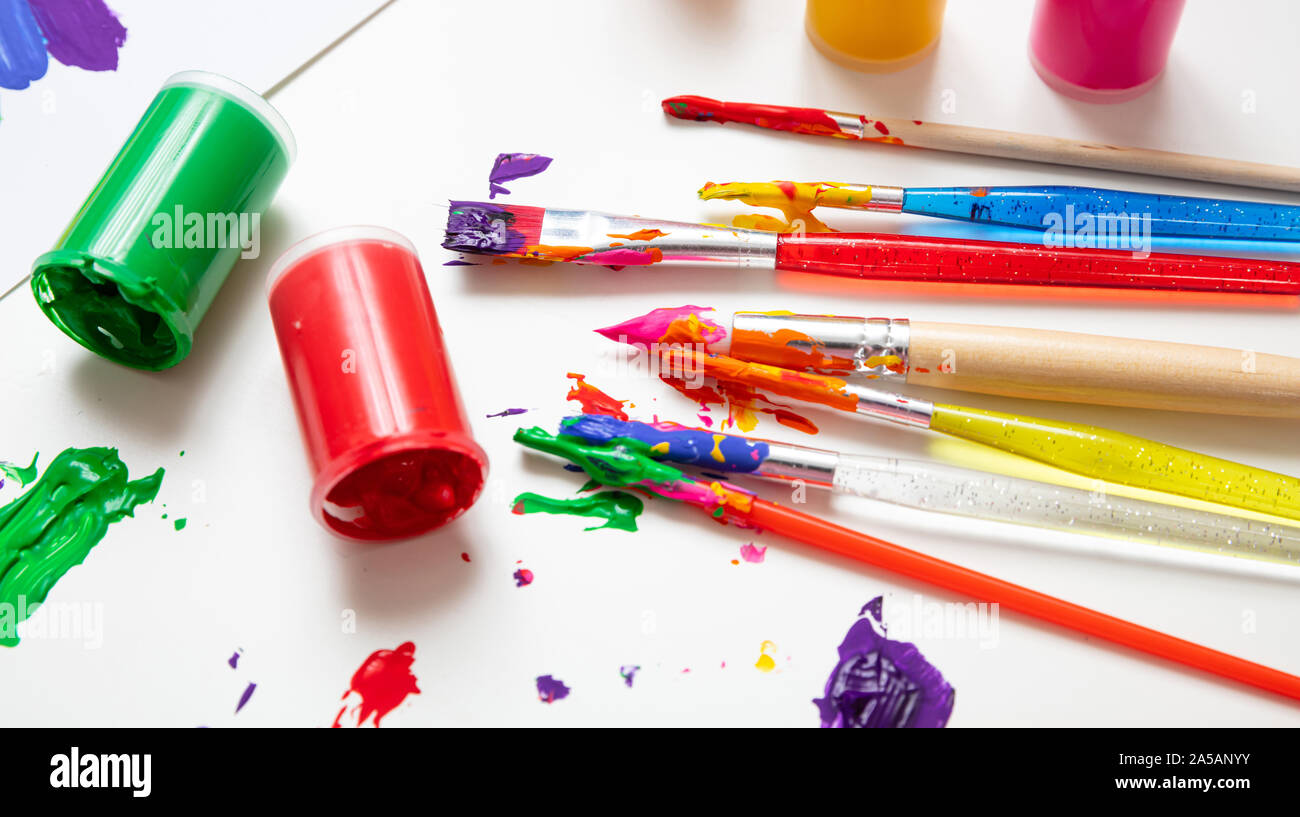 Kids creativity. Colorful finger paints set and paint brushes on white color background, closeup view Stock Photo