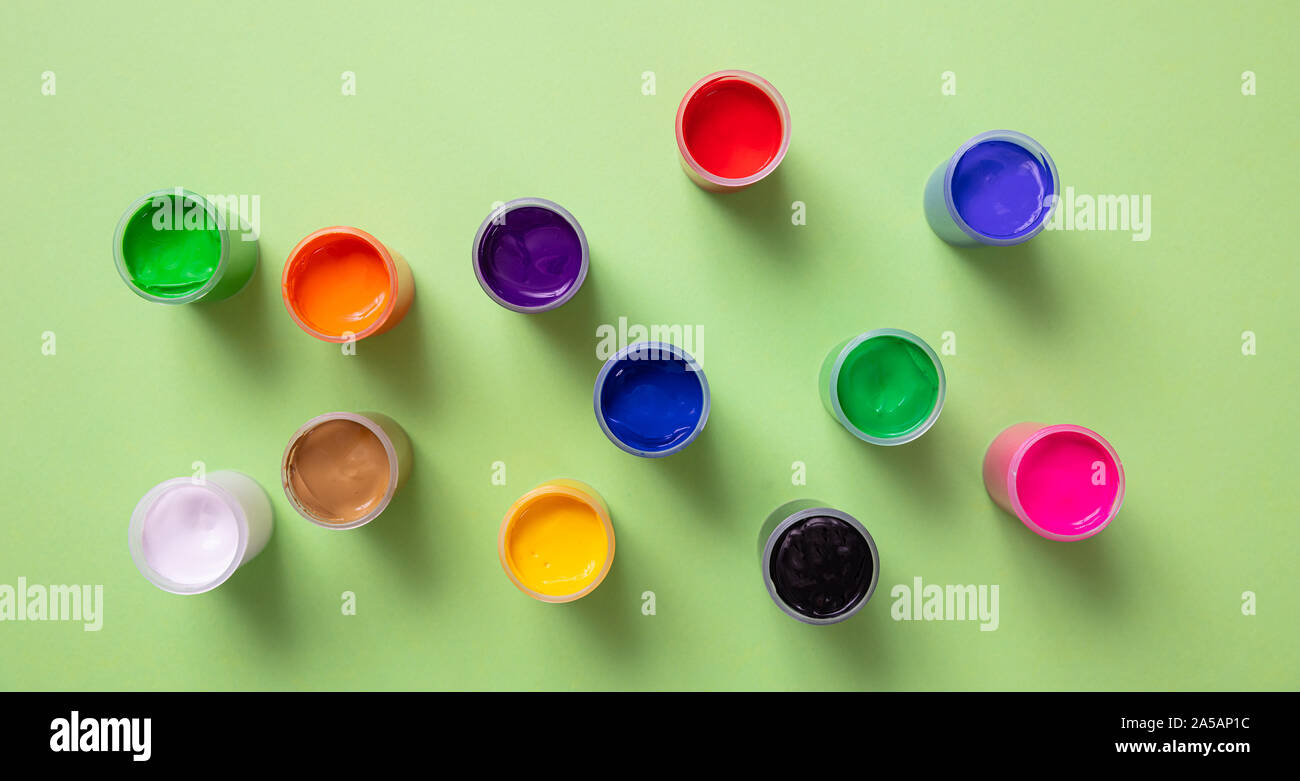 Kids creativity. Colorful finger paints set on pastel green color background, top view Stock Photo