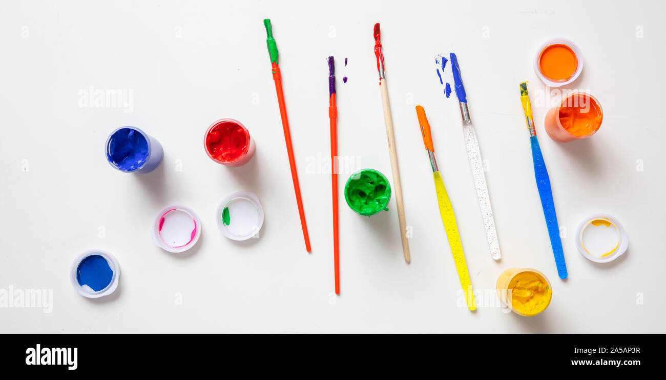 Kids creativity. Colorful finger paints set and paint brushes on white color background, top view Stock Photo