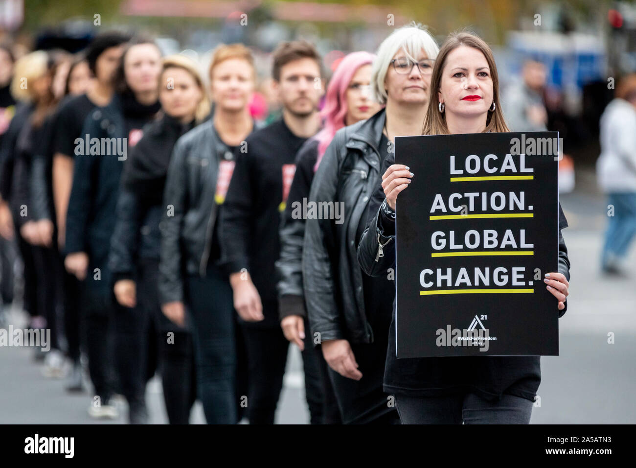 Berlin, Germany. 19th Oct, 2019. Participants of the worldwide 'Walk For Freedom' set a sign against human trafficking with a silent march. A woman's poster says 'Local action. Global change' (Local actions. Global change). The 'Walk For Freedom' also takes place in other German cities and all over the world. The organization A21, which fights human trafficking worldwide, called for the event. Credit: Christoph Soeder/dpa/Alamy Live News Stock Photo