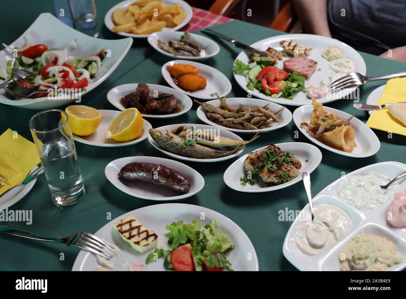 Huge meze meal served commonly in Cyprus. In this photo you can see different fish, sausages, vegetables, etc. on small plates on a table. Stock Photo