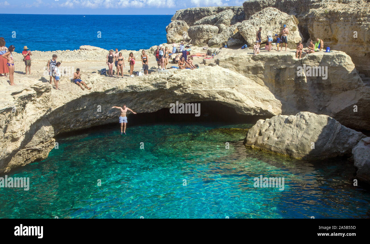 Man jumping into the Cave of Poetry, a famous natural pool, Roca Vecchia, Melendugno, Lecce, Apulia, Italy Stock Photo