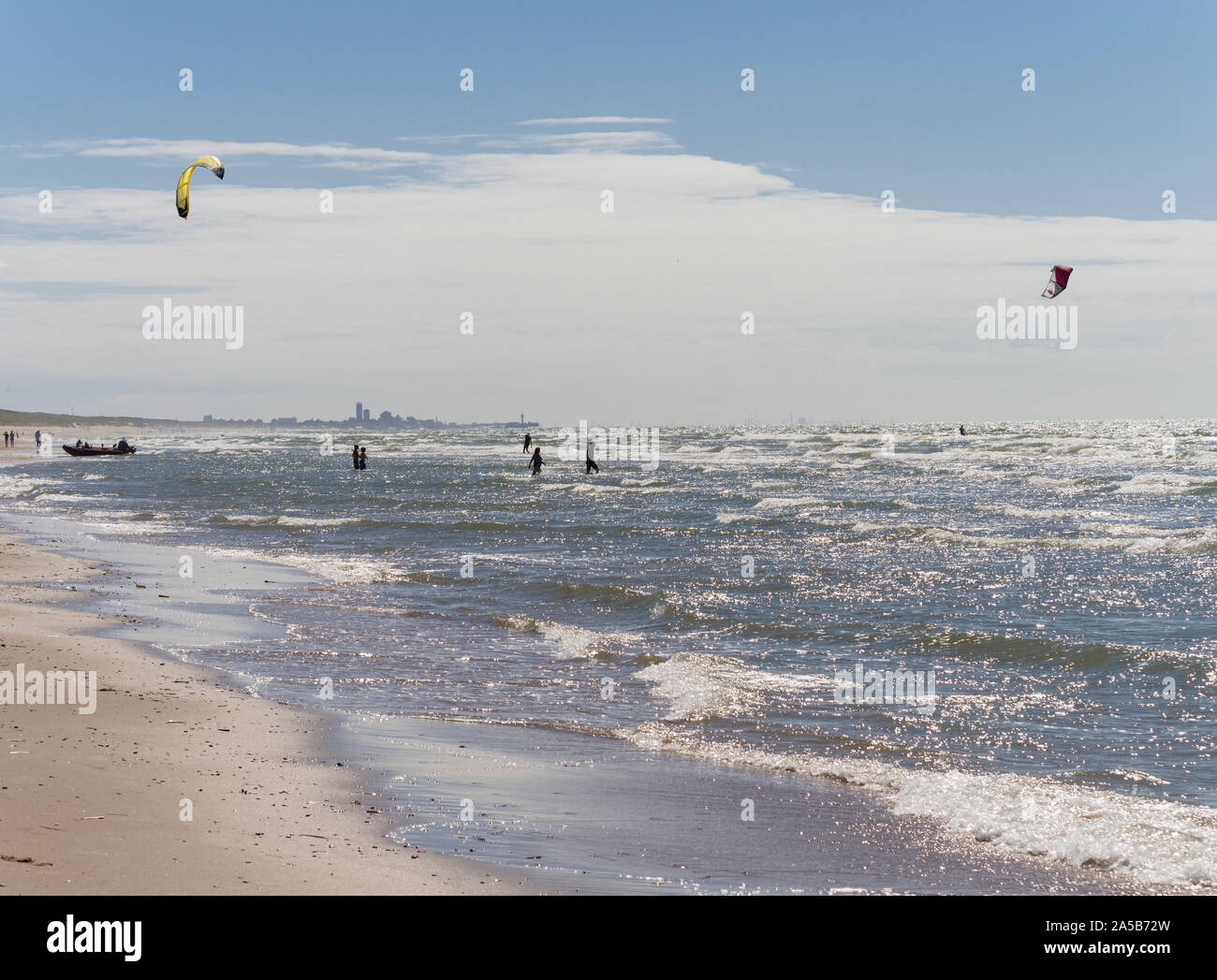Passing in front of the city skyline of The Haag (Den Haag), kite surfers are enjoying the stormy North Sea on a beach at Katwijk, Netherlands. Stock Photo