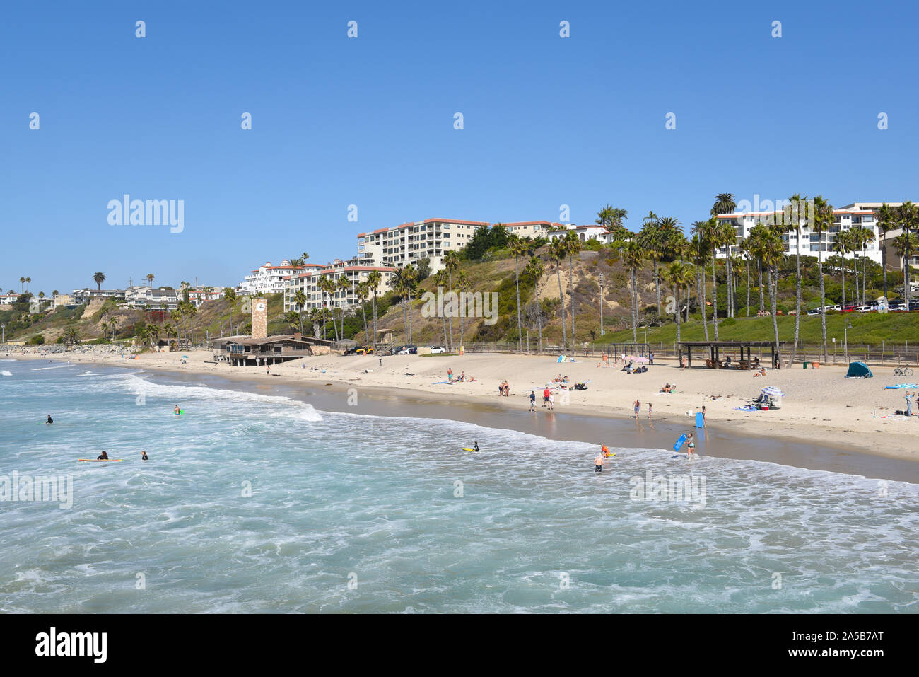 SAN CLEMENTE, CALIFORNIA - 18 OCT 2019: The beach and coastline with surfers and sunbathers seen from the pier in the South Orange County beach town. Stock Photo