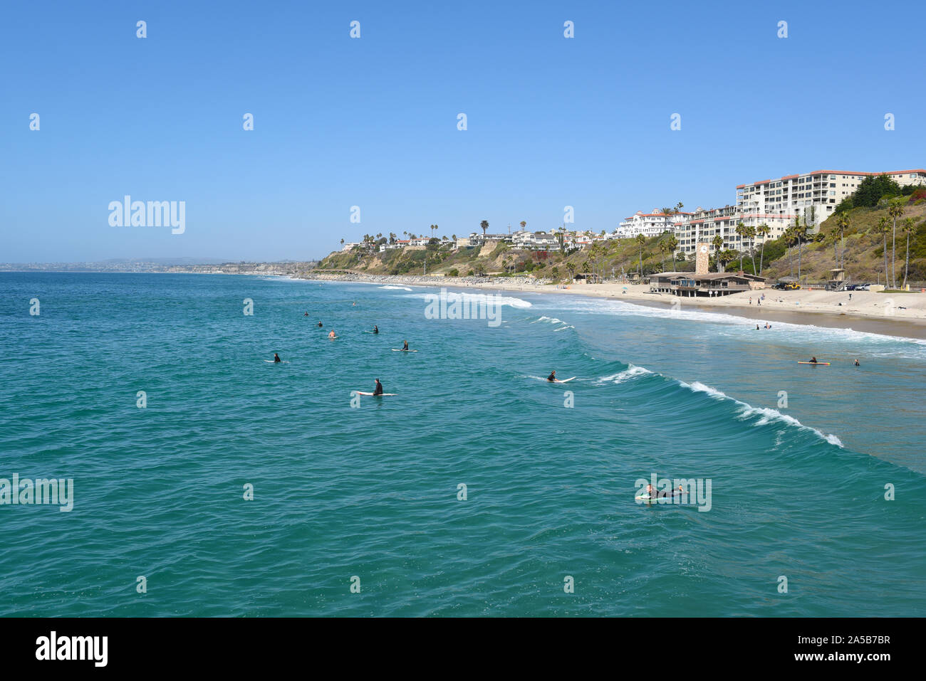 SAN CLEMENTE, CALIFORNIA - 18 OCT 2019: The beach and coastline with surfers and sunbathers seen from the pier in the South Orange County beach town. Stock Photo
