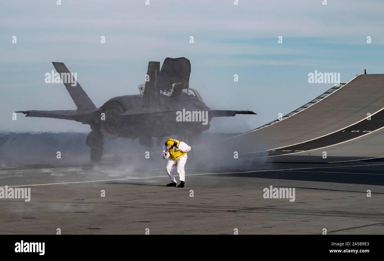 A Royal Navy sailor reacts as a F-35B Lightning stealth fighter aircraft launches from the flight deck of the HMS Queen Elizabeth during flight operations October 17, 2019 in the Atlantic Ocean. HMS Queen Elizabeth, is the largest warship ever built by the Royal Navy and is currently deployed in support of exercise WESTLANT 19. Stock Photo