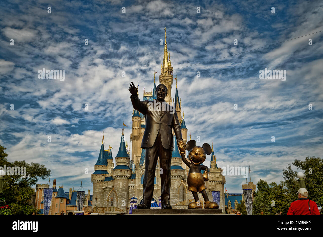 Cinderella's castle in Magic kingdom with Walt Disney and Mickey statue in foreground and clouds in sky in background, Orlando, Florida Stock Photo