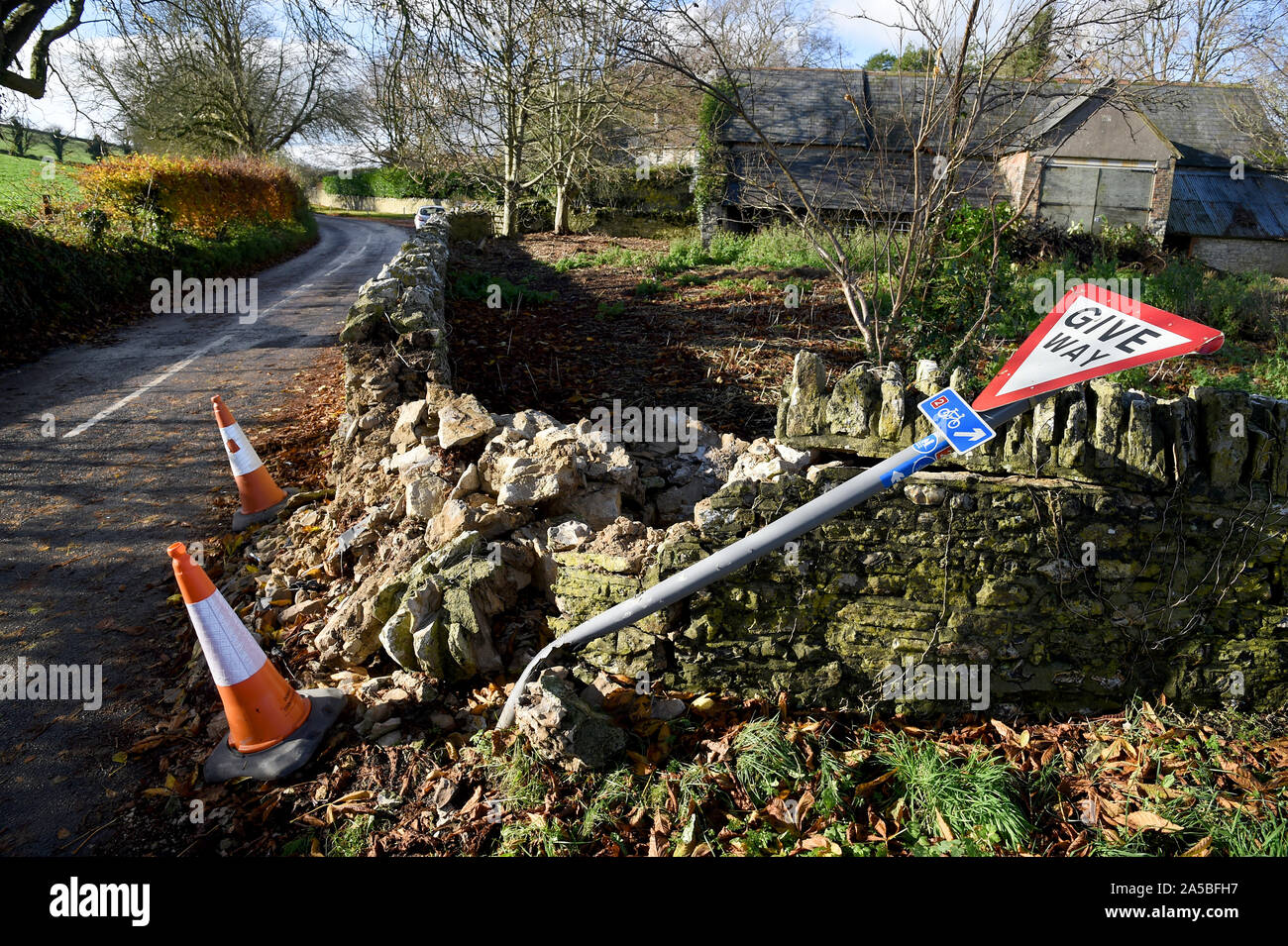 Give Way sign and wall that has been knocked down, England Stock Photo